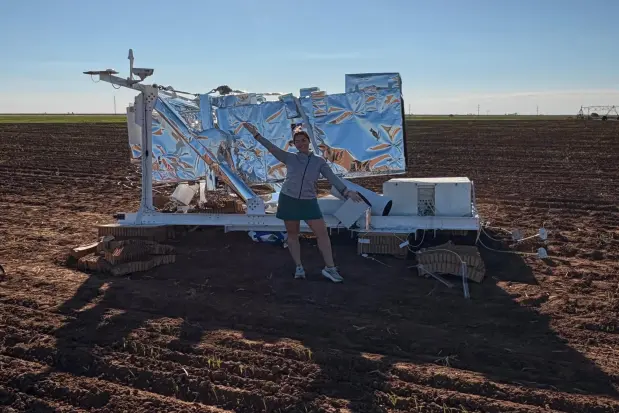 In this photo provided by Ann Walter, Ann Walter stands in front of a piece of NASA research equipment attached to a parachute that fell from the sky near her home in Edmonson, Texas, Thursday, Oct. 2, 2025. (Ann Walter via AP)