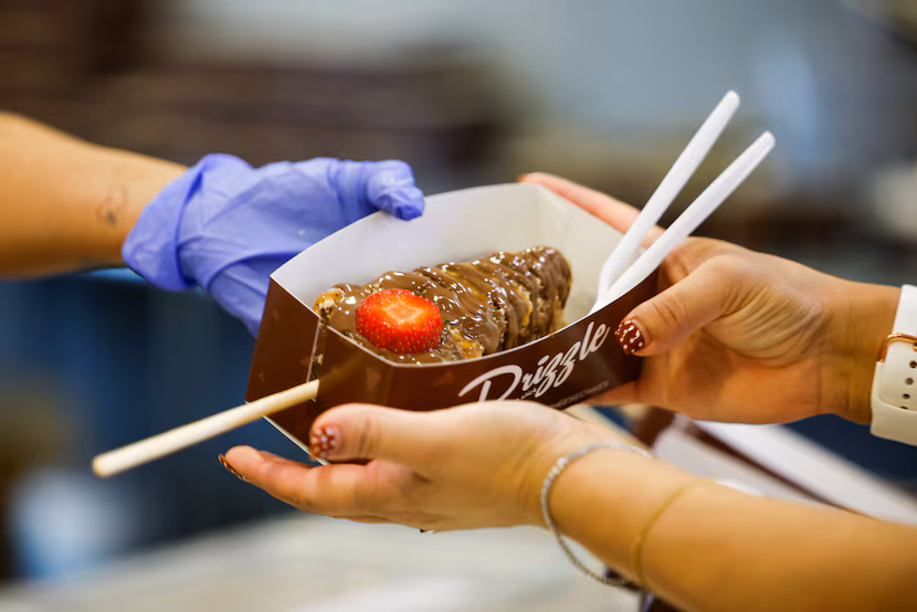 A customer gets the Hazelnut Deluxe Cheesecake from Drizzle Cheesecake at the State Fair of...