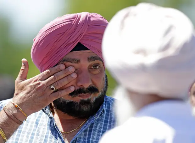 FILE – A man wipes away tears outside the Sikh...