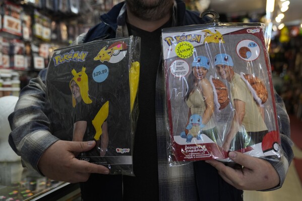 Owner Courtland Hickey holds a Pokemon costume from 2024, left, and one from this year, right, at Chicago Costume, Wednesday, Sept. 17, 2025, in Chicago. (AP Photo/Erin Hooley)