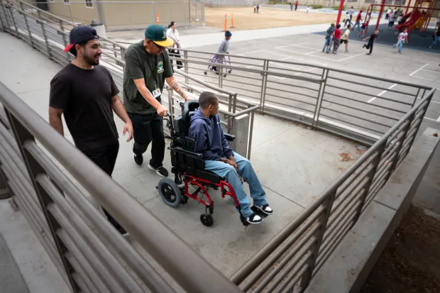 Humberto Rebollo and Jacob Pinedo assist Xavier Young to recess...