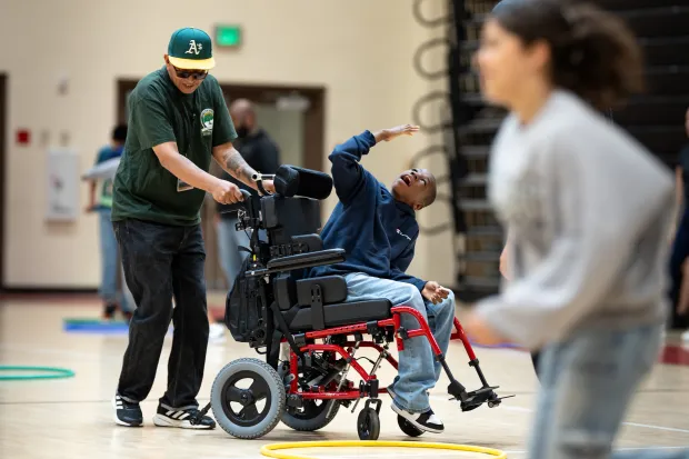 Xavier Young participates in gym class with the help of...