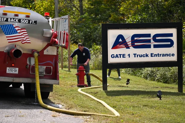 A person attaches a hose to a fire hydrant to...