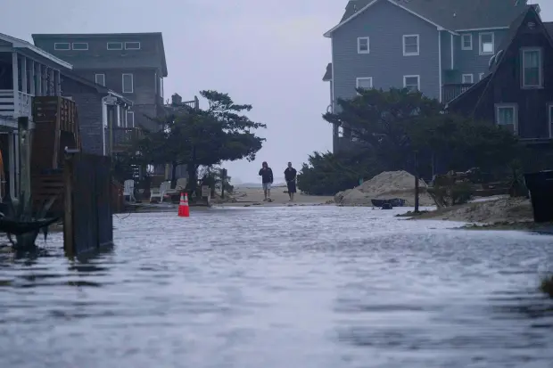 People look out at a flooded road in the midst...