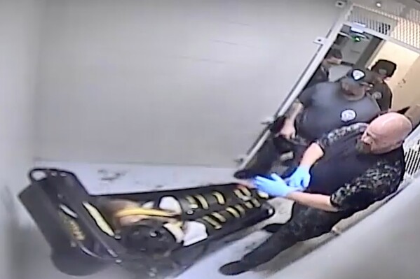 In this image from surveillance video provided by Jefferson City Correctional Center, jailers examine Othel Moore Jr., at the Jefferson City Correctional Center in Jefferson City, Mo., on Dec. 8, 2023, who according to an autopsy asphyxiated in the WRAP restraint. (Jefferson City Correctional Center via AP)