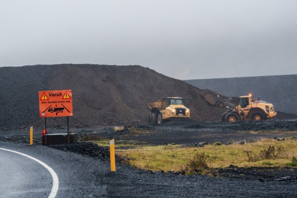Construction vehicles reinforce an area protecting Grindavik, Iceland, Friday, Oct. 13, 2025. (AP Photo/Marco di Marco)