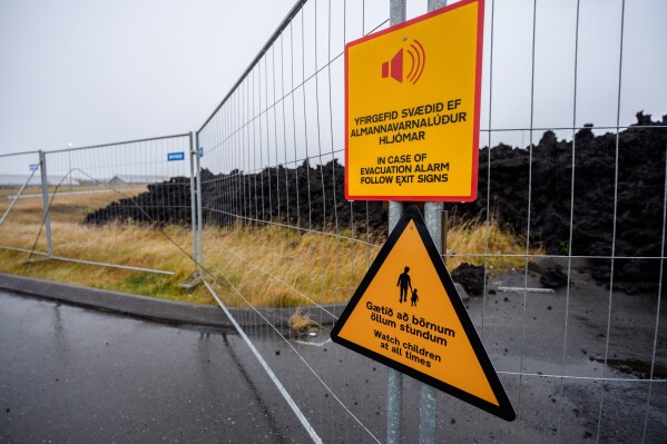Warning signs are displayed at a fenced-off lava field in Grindavik, Iceland, Monday, Oct. 13, 2025, from an eruption on Jan. 14 2024. (AP Photo/Marco di Marco)