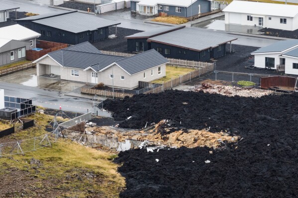 A house, destroyed by lava, is visible on the edge of a hardened flow Friday, Oct. 10, 2025, that reached Grindavik, Iceland, from a Jan. 14 2024, eruption. (AP Photo/Marco di Marco)