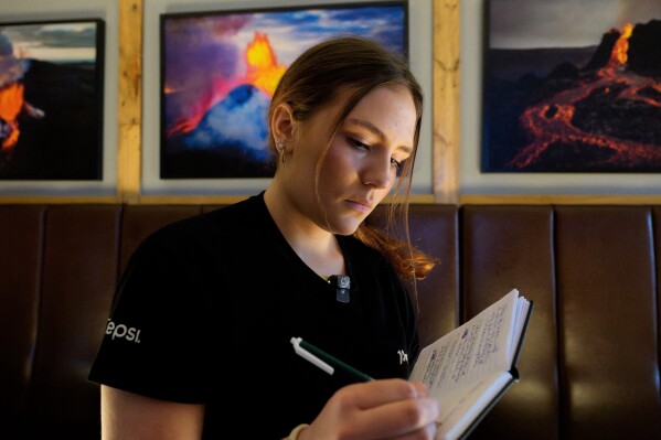 Kristólína Ósk Guðjónsdóttir writes notes while working at Papas restaurant in Grindavik, Iceland, Friday, Oct. 10, 2025. (AP Photo/Marco di Marco)