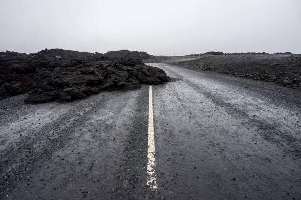 The old road leading to the Blue Lagoon spa and resort outside Grindavik, Iceland, is partly buried by lava Monday, Oct. 13, 2025, from one of the 2024 eruptions. (AP Photo/Marco di Marco)
